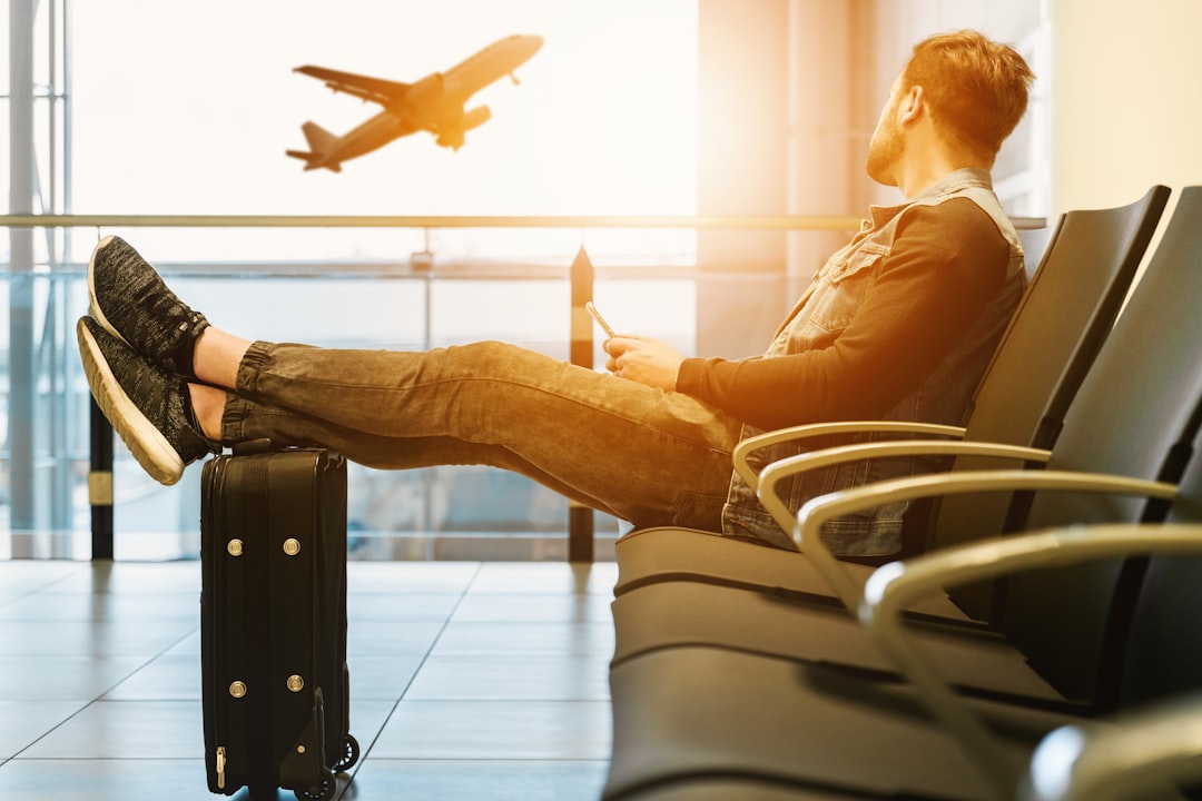 A cozy travel setup with a neck pillow, blanket, and snacks on a plane or train seat.